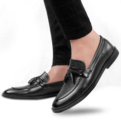 Black leather loafers worn with black pants on a white background