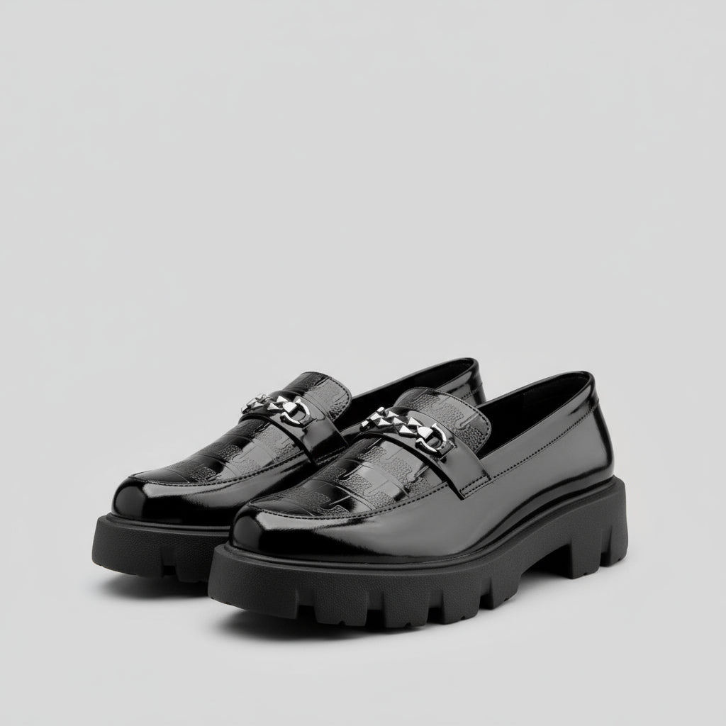 Black loafers with chunky soles on a yellow and white background, featuring the Buxy brand.