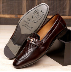 Brown loafers with a decorative buckle on a wooden surface