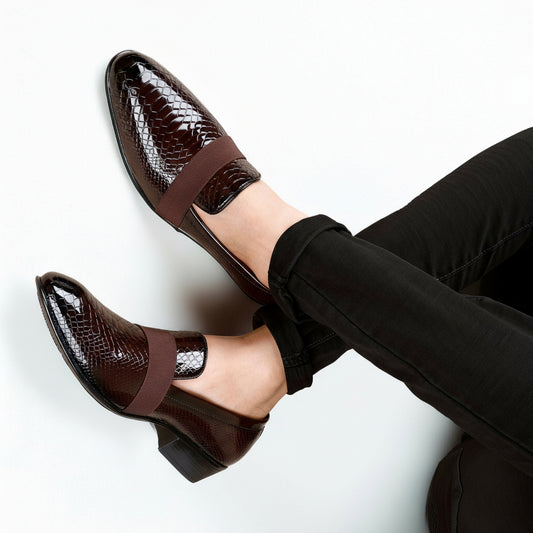 Brown patent leather shoes with a strap worn by a person on a white background