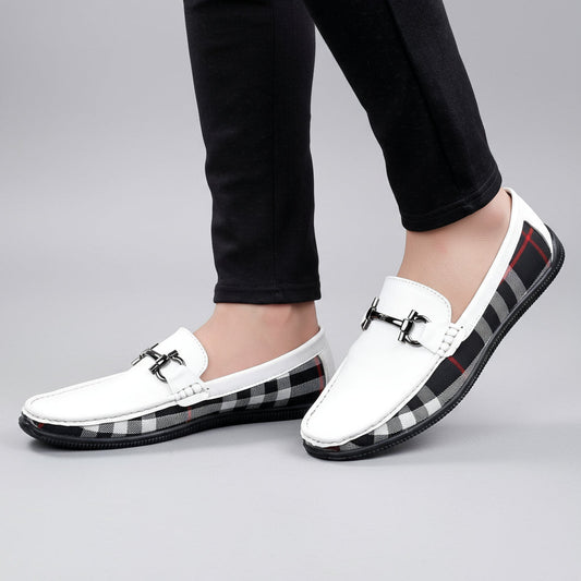 White loafers with plaid pattern on soles worn by a person on a wooden floor.