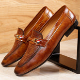 Brown leather loafers with a decorative buckle on a wooden surface