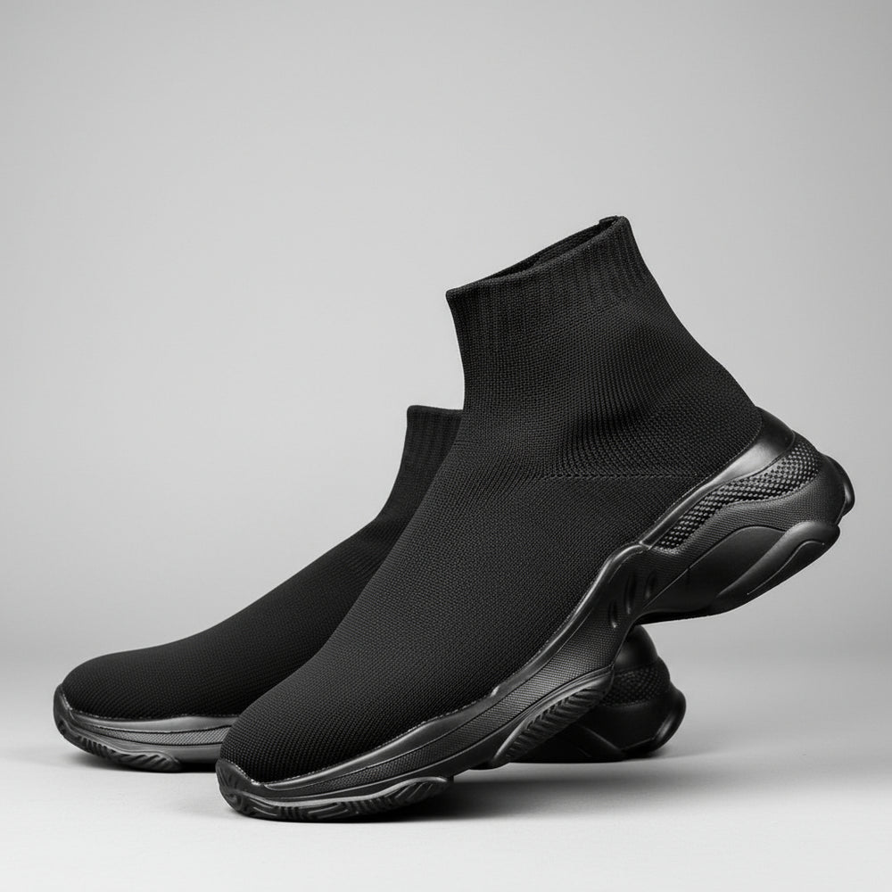 Black sock shoes worn by a person on a dark background