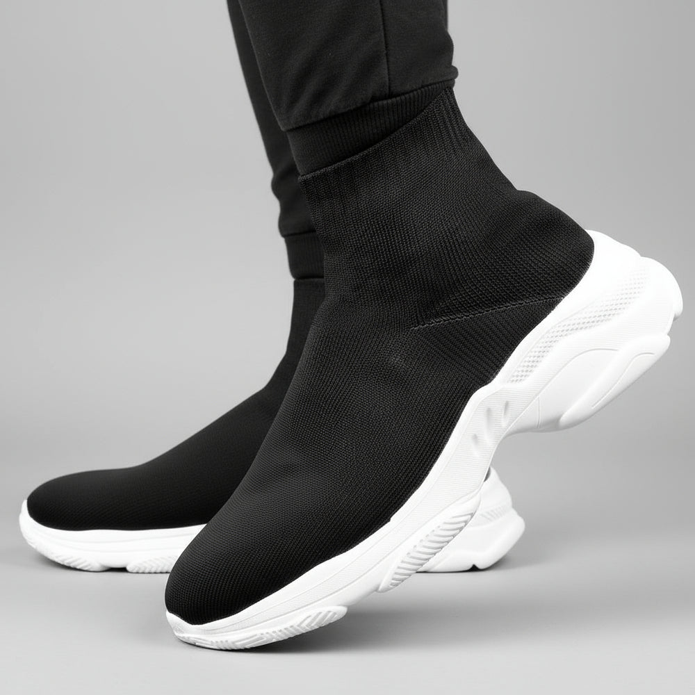 Black sock shoes with white soles worn by a person on a dark background