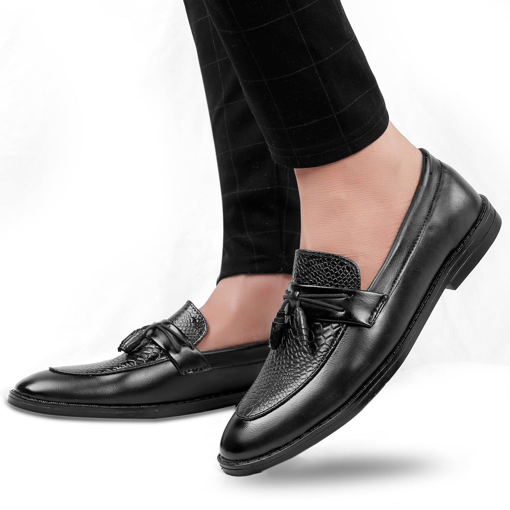 Black leather loafers worn with black pants on a white background
