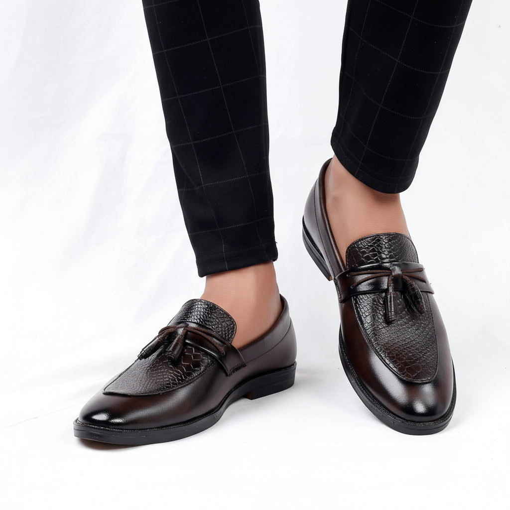 Brown leather loafers worn with black checkered pants on a white background