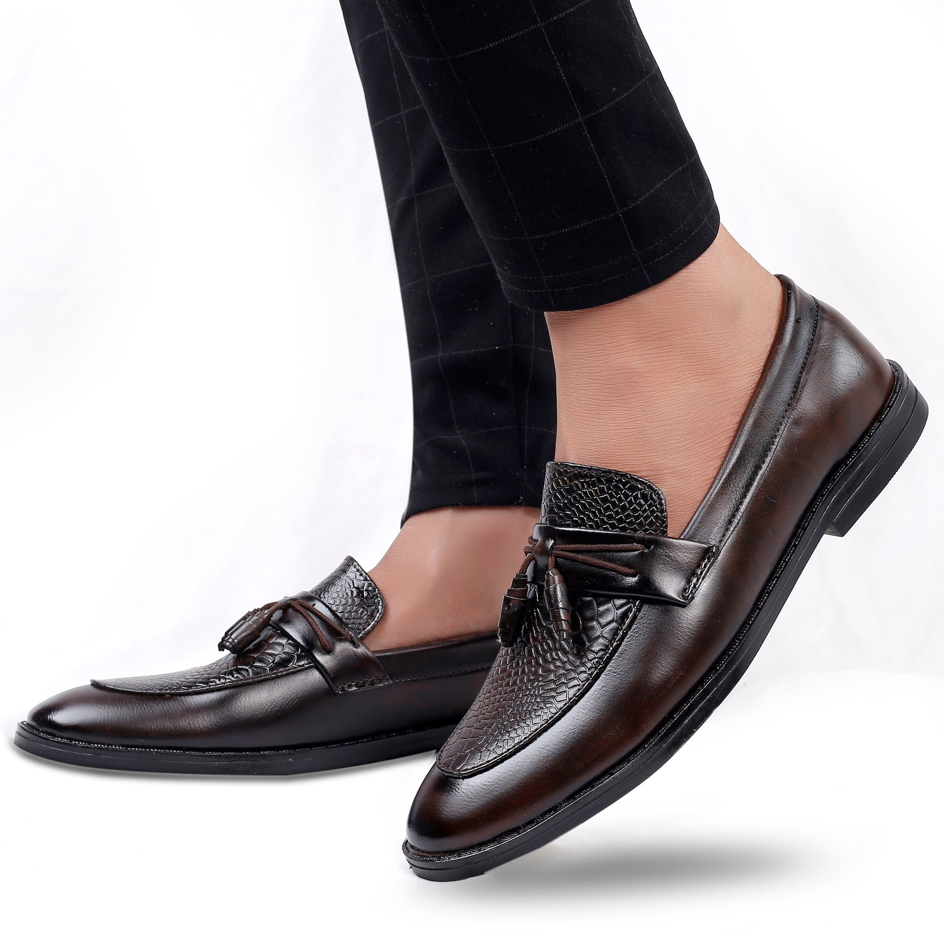 Brown leather loafers worn with black checkered pants on a white background