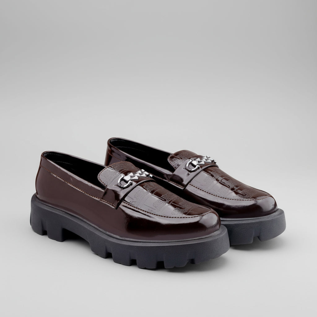 Brown loafers with thick soles on a yellow and white background, featuring Buxy brand logo.