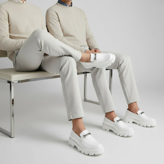 White loafers with chunky soles on a gray and beige background, featuring the Buxy brand.