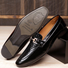 Black leather loafer shoe with a brand logo on a wooden surface