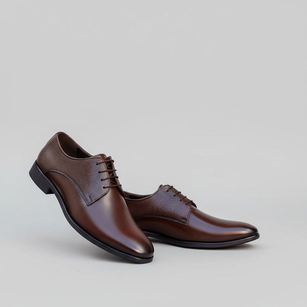 Brown dress shoes worn by a person sitting on steps indoors.