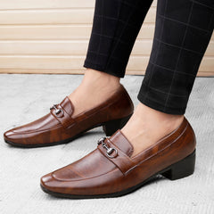 Brown leather loafers worn with black checkered pants on a light background