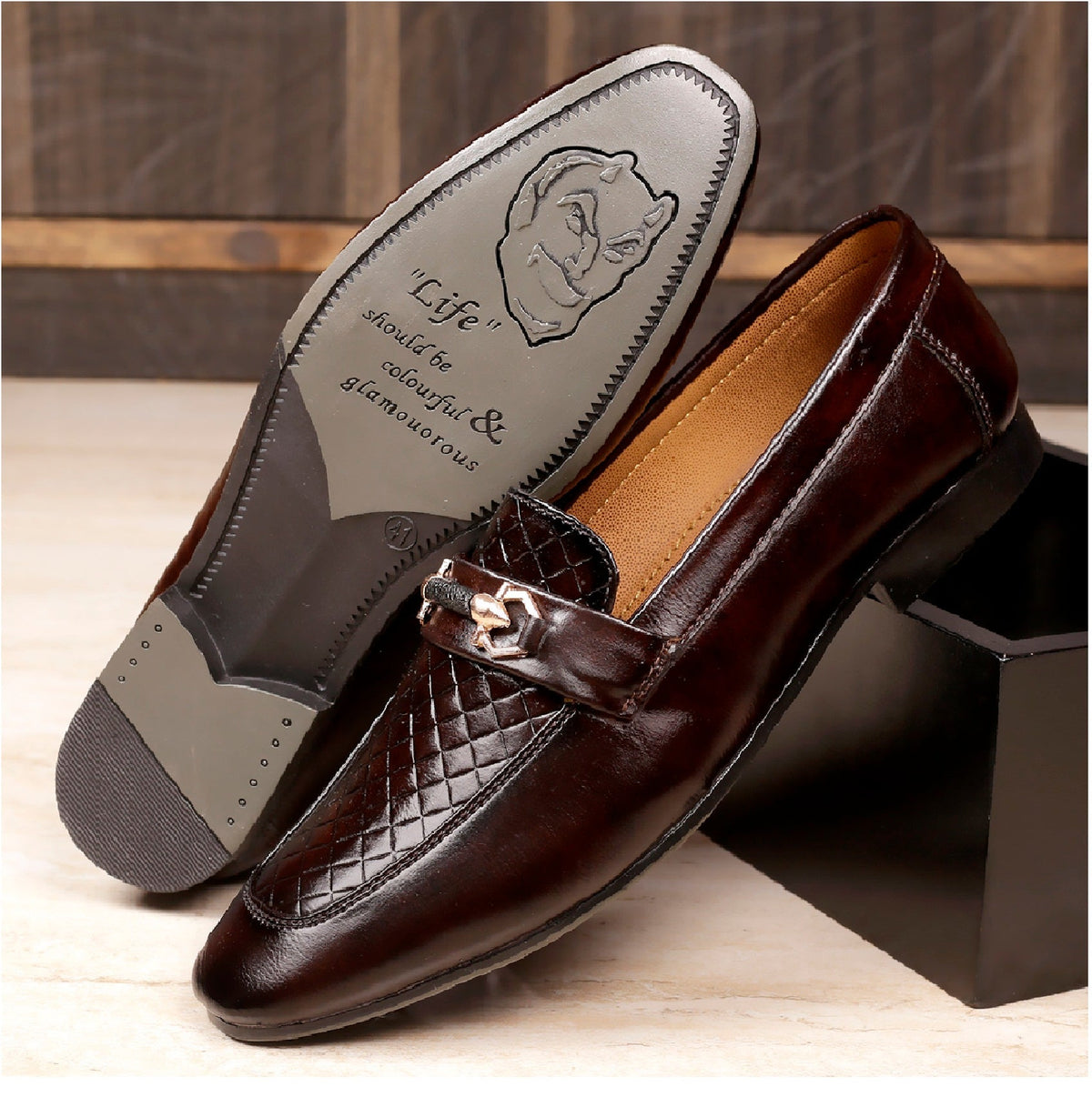 Brown loafers with a decorative buckle on a wooden surface