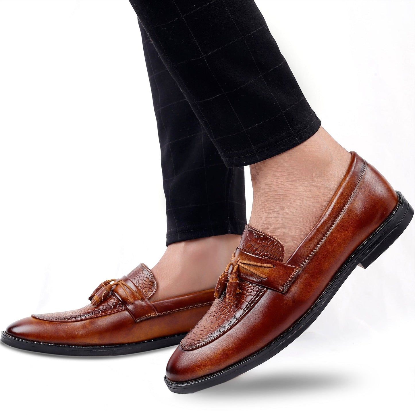 Brown loafers worn with black checkered pants on a white background