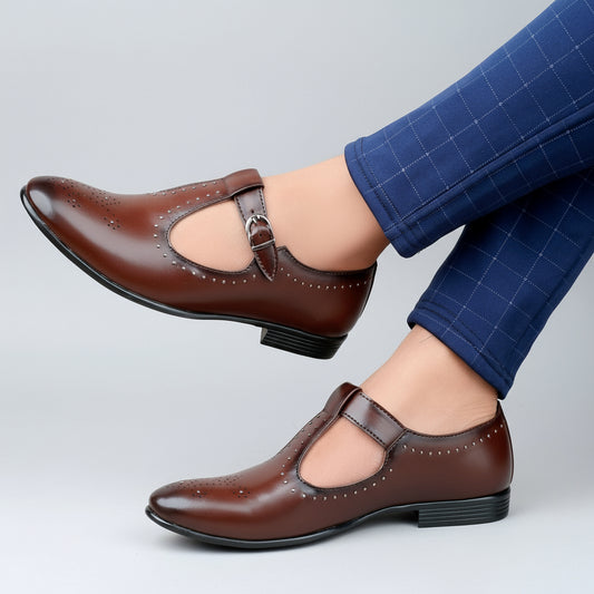 Brown shoes with a strap worn by a person in blue pants on a wooden floor.