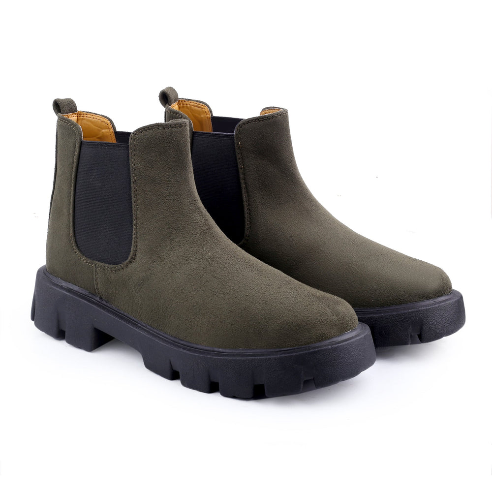 Pair of green Chelsea boots with black soles on a white background