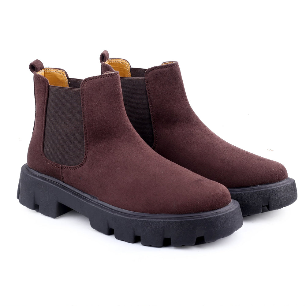 Pair of brown Chelsea boots with black soles on a white background