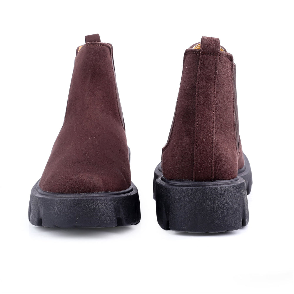 Brown suede boots with black soles on a white background