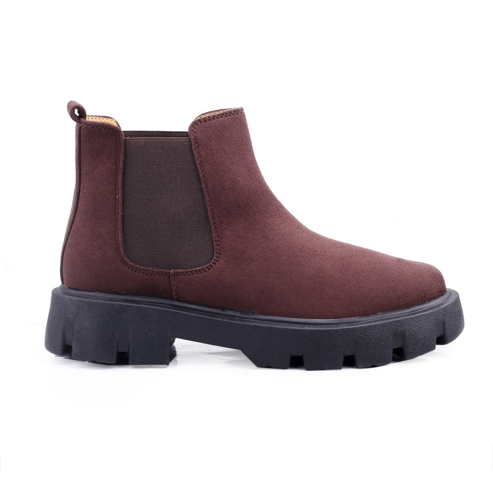Brown Chelsea boot with a thick black sole on a white background