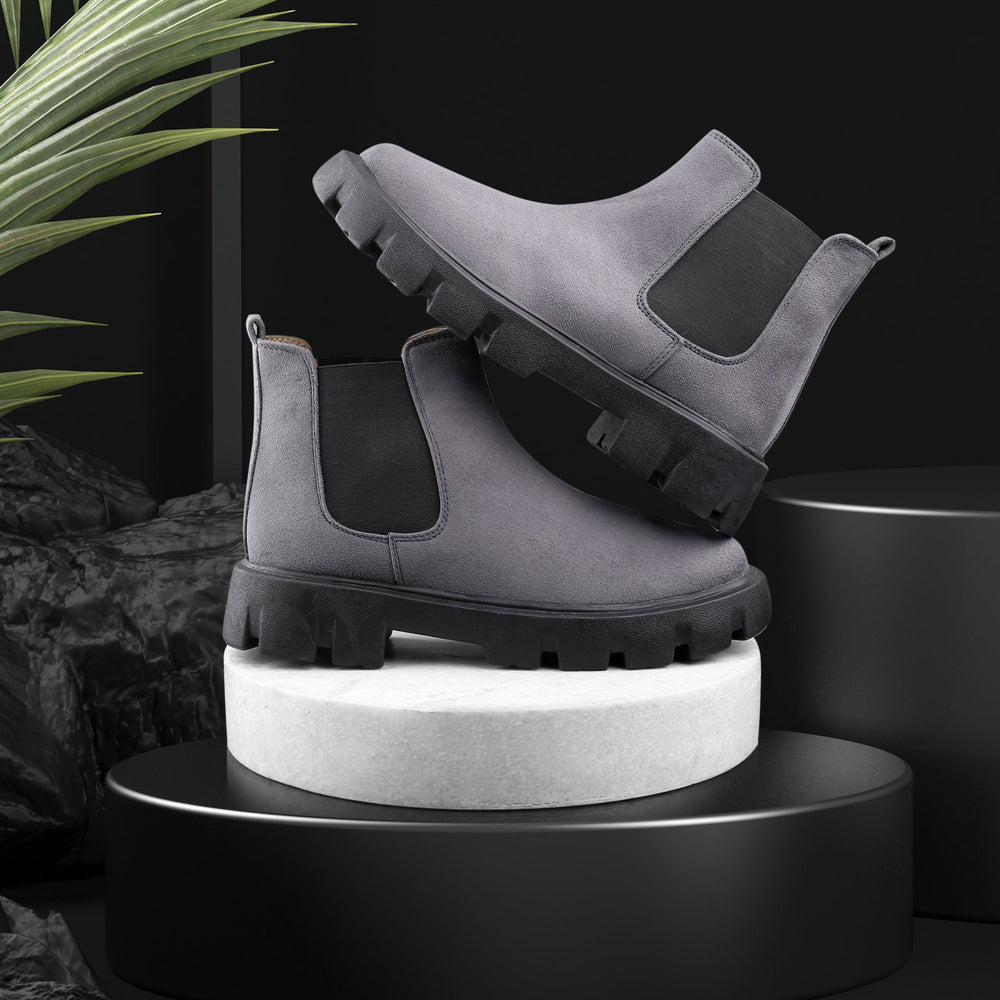 Gray Chelsea boots on a black platform with a dark background