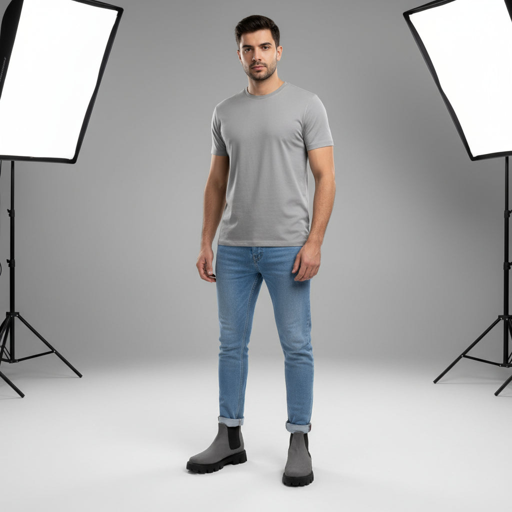 Gray Chelsea boots worn with light blue jeans on a gray pavement background