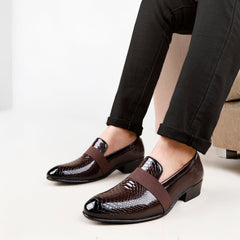 Brown dress shoes with snake print strap worn by a person sitting on a white background