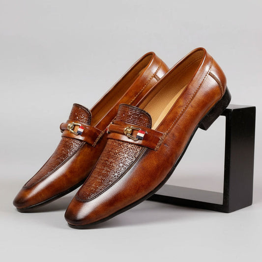 Brown leather loafers with a decorative buckle on a wooden surface
