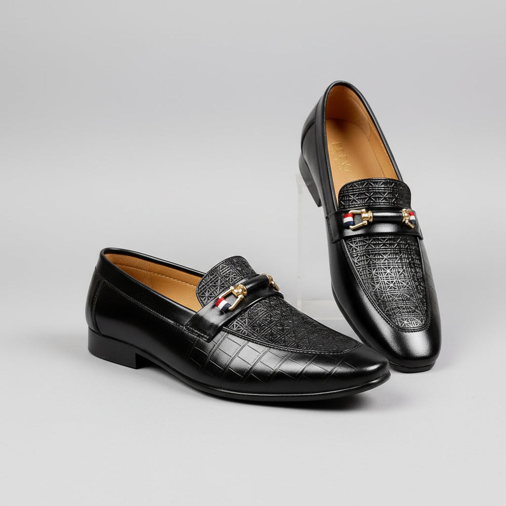 Black leather loafers with gold accents on a wooden surface