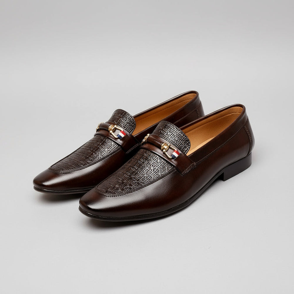 Brown leather loafers with a decorative buckle on a wooden surface