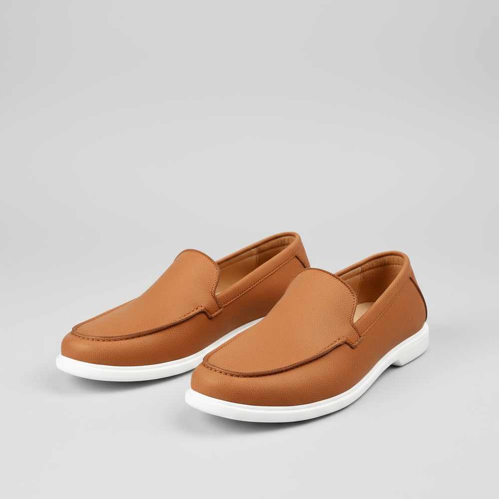 Brown loafers being worn on a light wooden floor