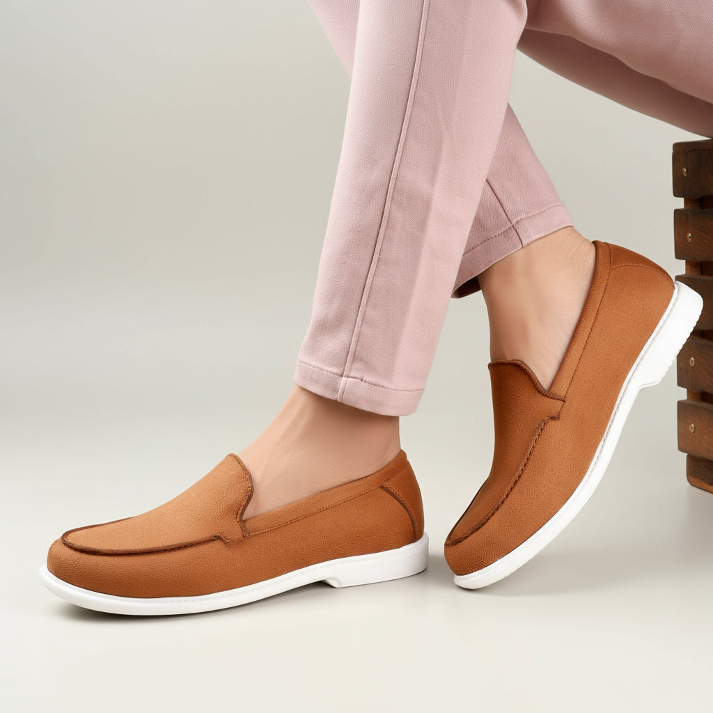 Brown loafers with white soles worn by a person sitting indoors.