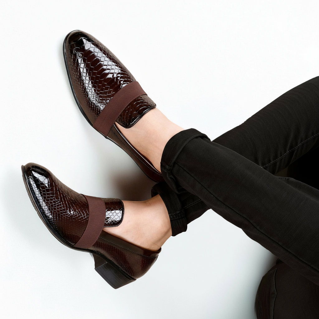 Brown patent leather shoes with a strap worn by a person on a white background