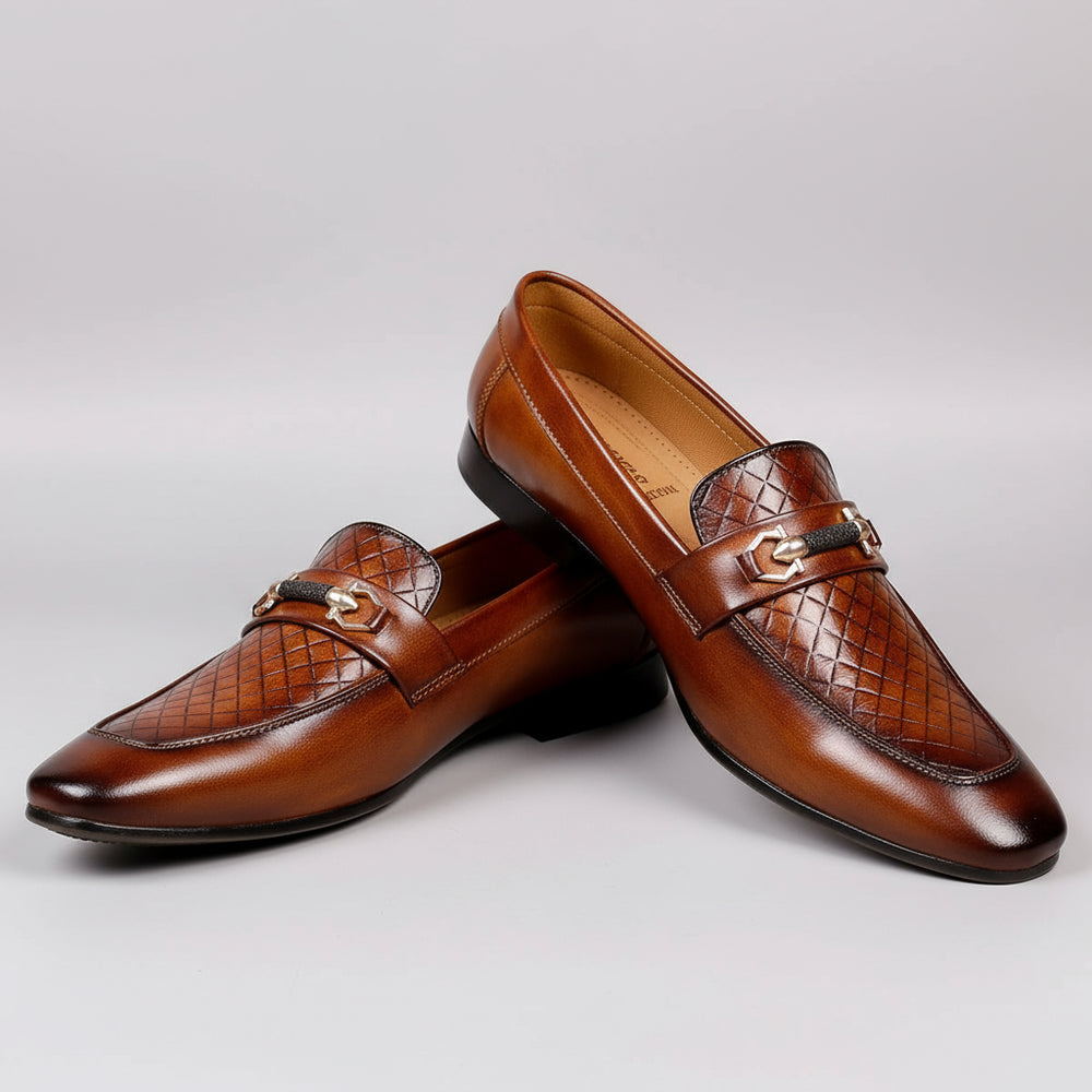 Brown leather loafer shoe with decorative buckle on a wooden surface