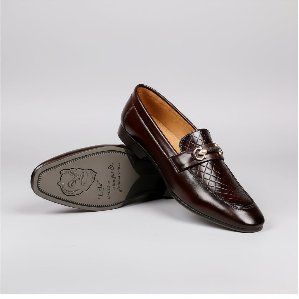 Brown loafers with a decorative buckle on a wooden surface