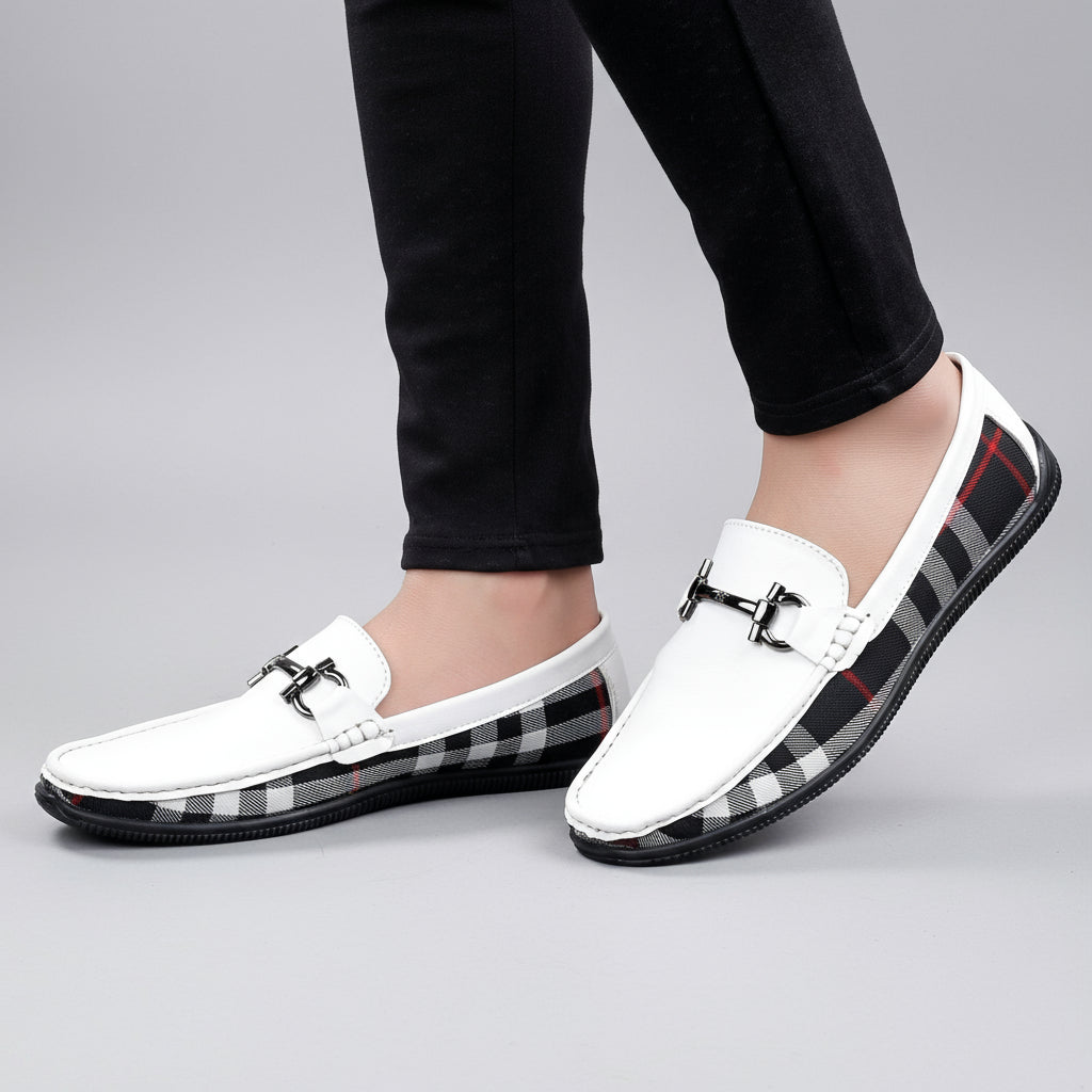 White loafers with plaid pattern on soles worn by a person on a wooden floor.