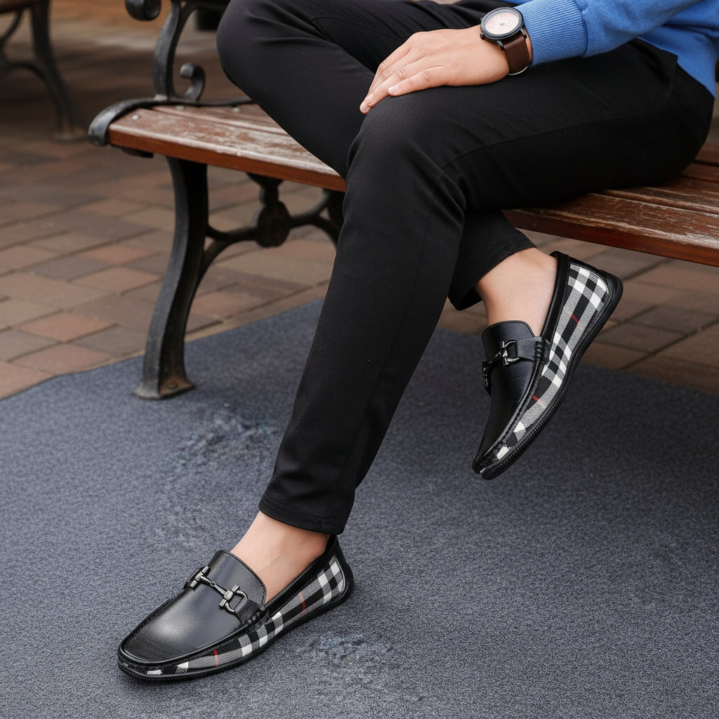 Person wearing black and plaid loafers on a gray carpet