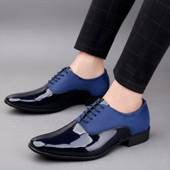 Blue and black dress shoes worn with black pants on a neutral background