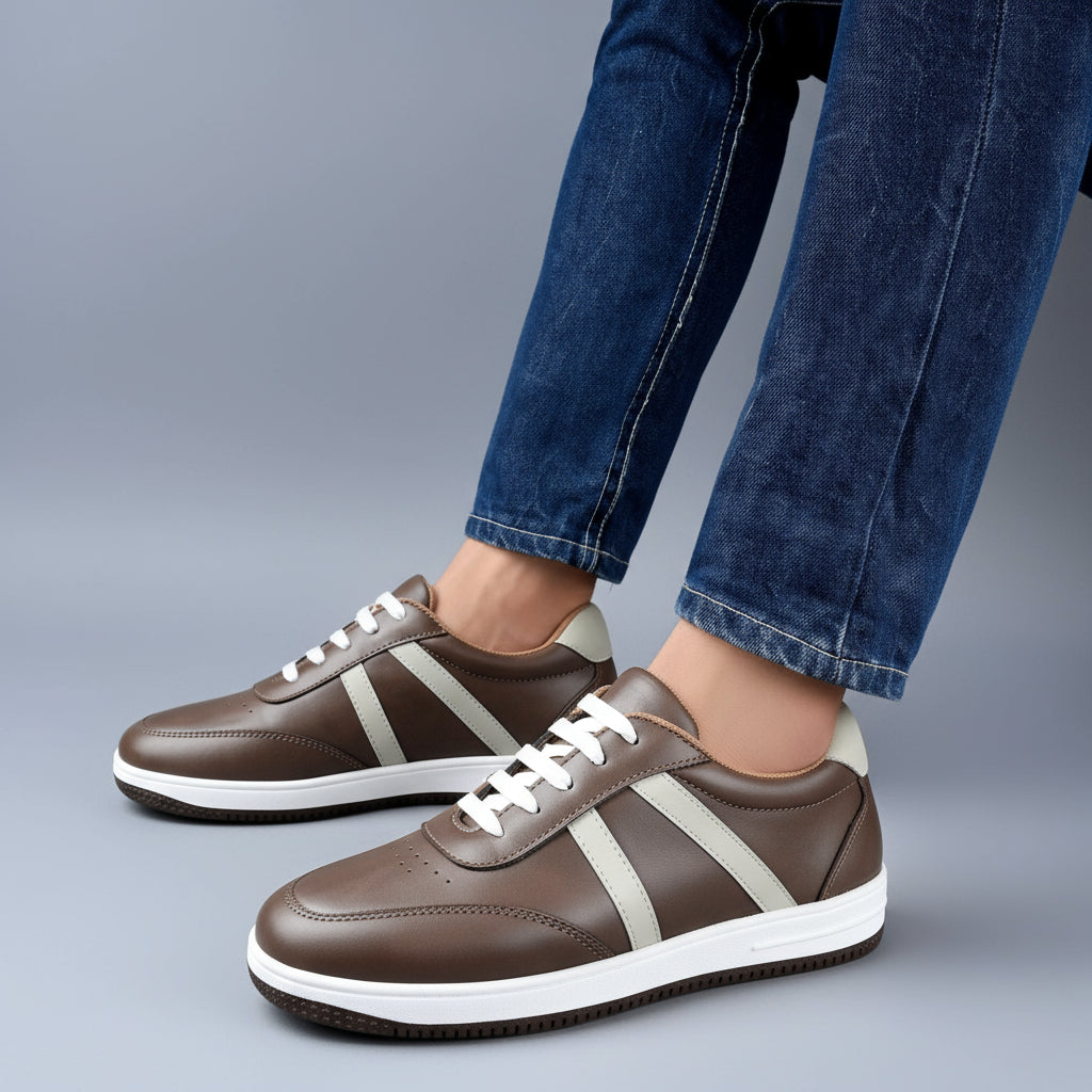 Brown sneakers with white stripes worn with blue jeans on a wooden floor.