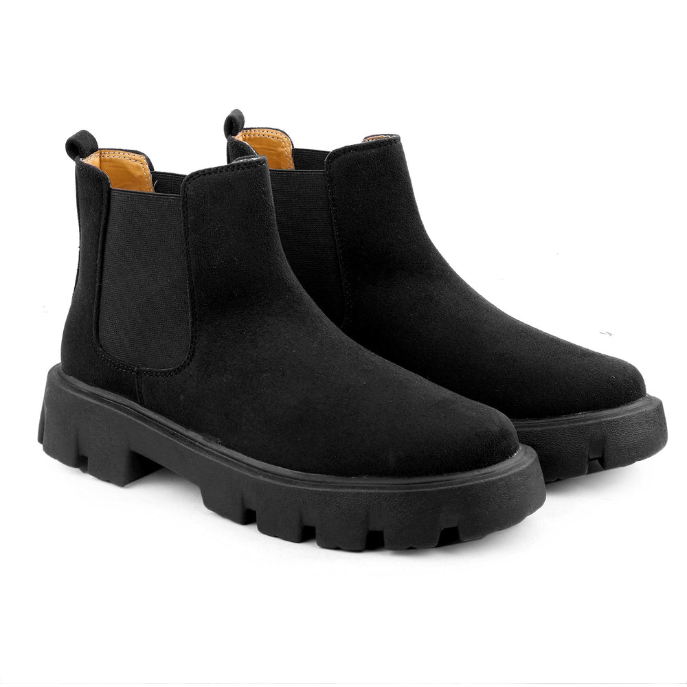 Black Chelsea boots with thick soles on a white background