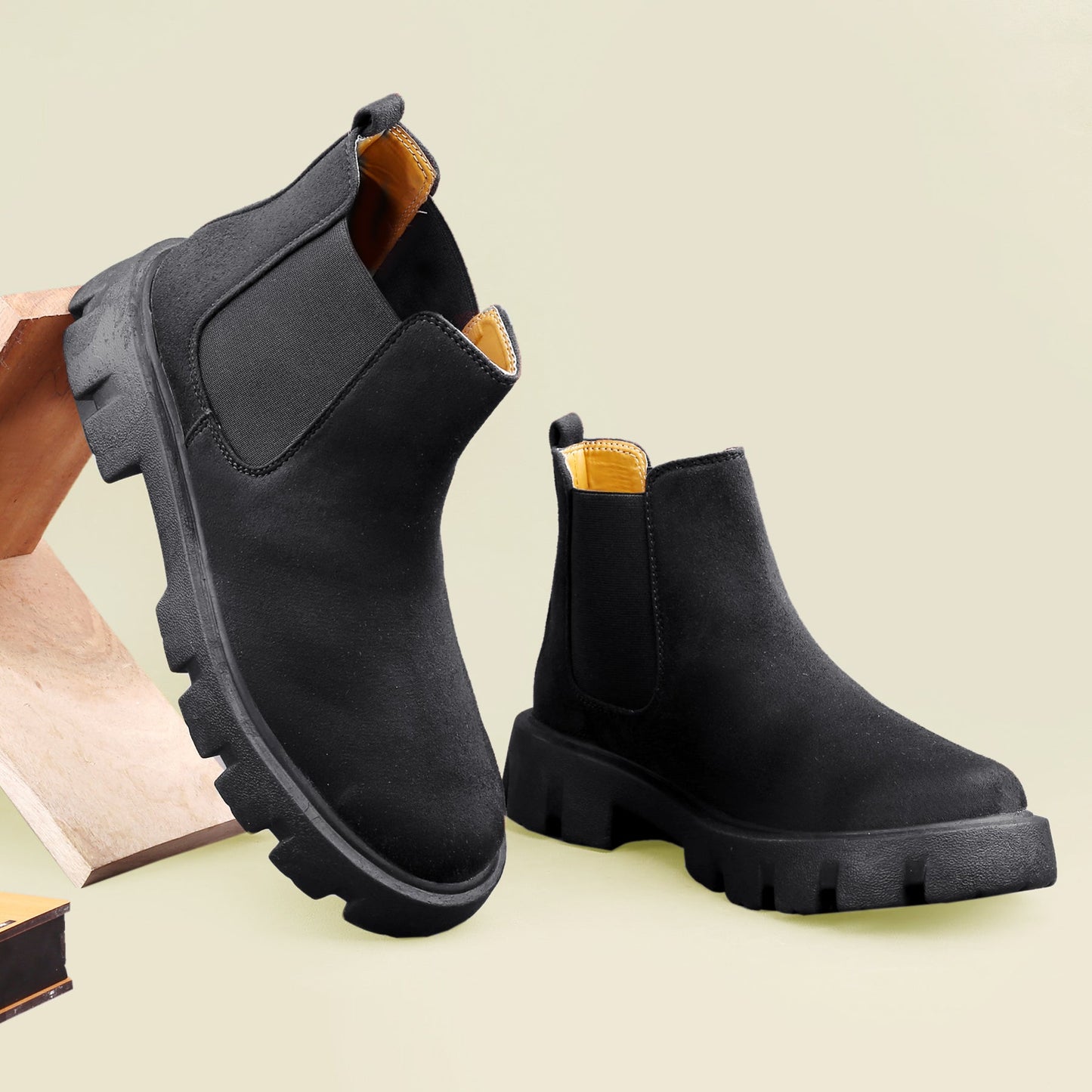 Black Chelsea boots on a light green background