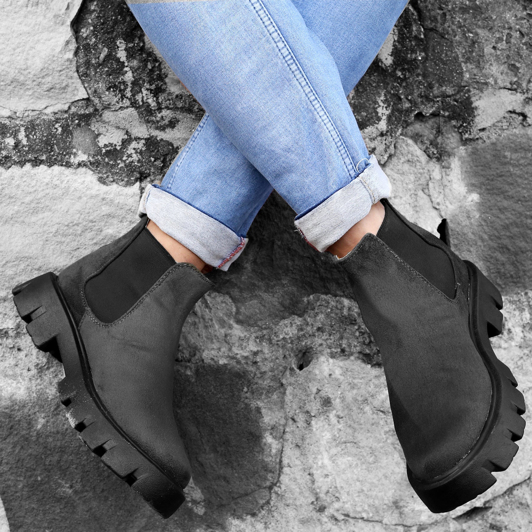 Person wearing black Chelsea boots on a stone surface