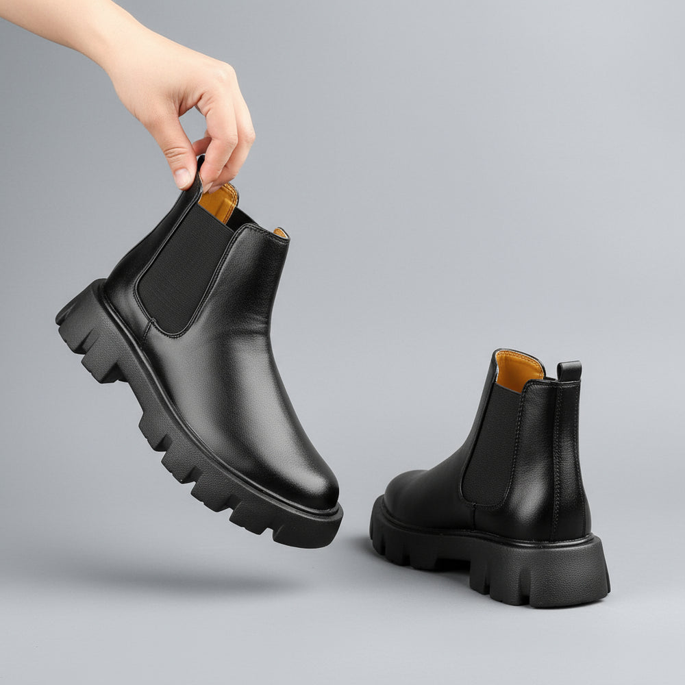 Black leather Chelsea boots on a light blue background
