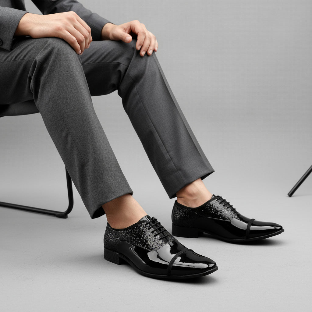 Black glossy dress shoes on a white platform with a gray background